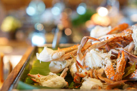 steamed blue crab or horse crab orange on wood tray and banana leaf for lunch or dinner serve on seafood buffet restaurant at hotel with warm light bokeh on delicious foodの写真素材