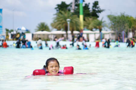 Asian child or kid girl swimming wear life jacket for safety and smiling with happy fun on swimming...