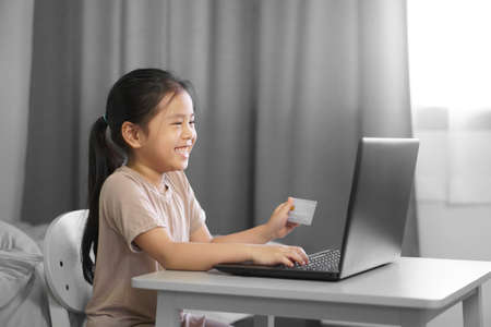 Asian child happy or kid girl smile holding credit card for enjoy online shopping and electronic...