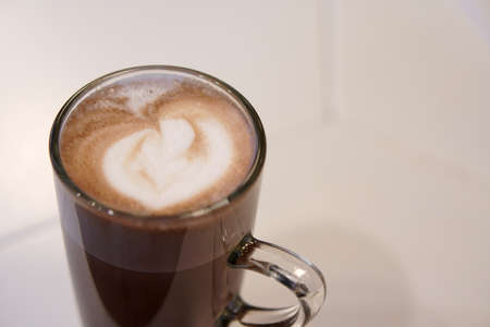 closeup hot cocoa or chocolate and mocha with milk froth in clear glass cup on table in cafe or...