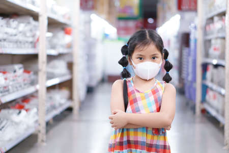 Asian child or kid girl wear N95 face mask for close mouth and sick on nose with cold cough and protect influenza virus or PM2.5 dust smoke and bacteria for shopping in department store or supermarketの写真素材