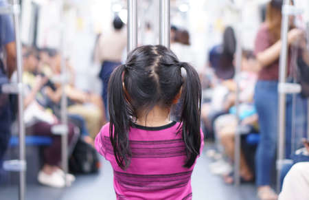back of asian child or kid girl enjoy standing in bogey of sky train or electric train with underground railways or subway metro and holding rail for happy travel or transportation fun in city streetの写真素材