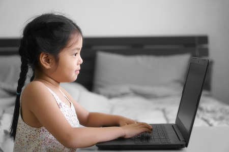 Asian child student or kid girl study online or work from home on computer notebook or play laptop...