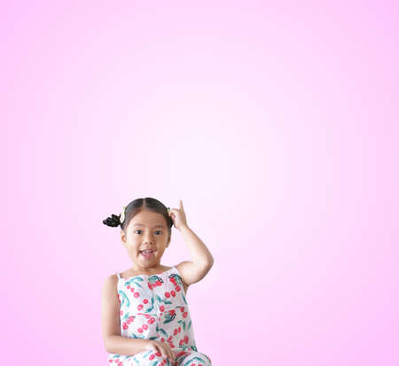 Asian child wow or kid girl thinking  finger point up on top for new idea to imagination education  smiling happy at nursery pre school on pink space background isolatedの写真素材