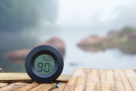air thermometer and hygrometer or humidity on 15 degrees temperature to cool on wooden carriage and river or stream with tree in green jungle for summer or winter holiday relax and vacation travelの写真素材