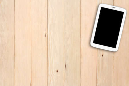white tablet with empty black display on top view and blank brown wooden table for social distancing and business work from home or online teach to study at home by school on internet from coronavirusの写真素材