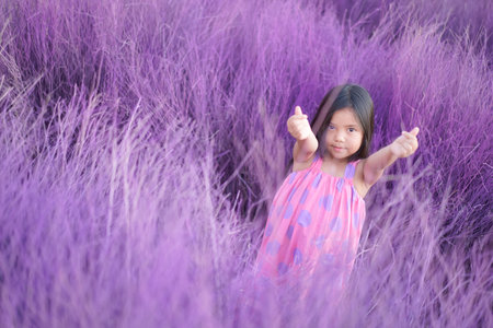 Asian child cute or kid girl lovely smile and make two finger hand mini heart for love valentine day or wedding happy with wearing pink dress on garden meadow or purple grass and violet lavender fieldの写真素材