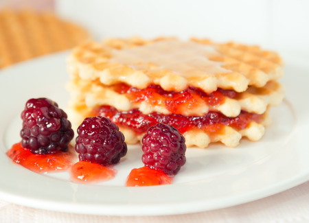 Golden waffles with raspberries and jamの写真素材
