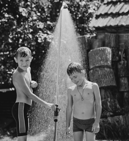 Boys under a shower in the garden in hot dayの写真素材