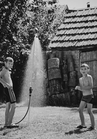 Boys under a shower in the garden in hot dayの写真素材