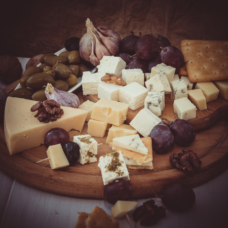 Variety of cheese with nuts and olives on the wooden plateの写真素材