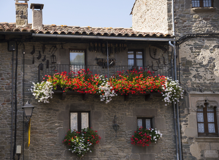 RUPIT I PRUIT, CATALONIA, SPAIN - OCTOBER 04, 2016: Windows with large red and white flowers of pelargoniumのeditorial素材