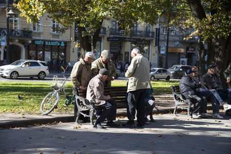 LVIV / UKRAINE - OCTOBER 06, 2018: A group of older men resting on the benches on  the autumn day. Lviv, Svobody Ave. Ukraineのeditorial素材