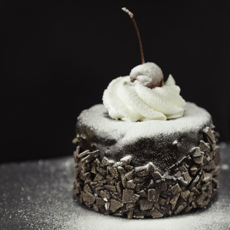 Delicious chocolate cake with red cherry on the black backgroundの写真素材