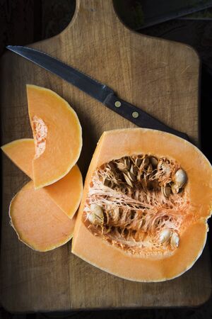 Half of the fresh pumpkin and slices of pumpkin on the tableの写真素材