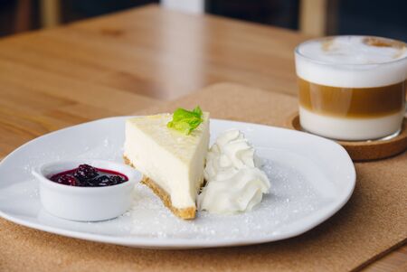 Slice of cheesecake with fruits on a plate and cappuccino. Space for textの写真素材