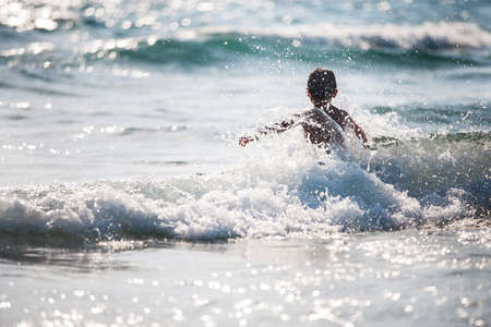 A little boy on the beach, playing with the waves, summer time. Concept of relaxation and a healthy lifestyleの写真素材