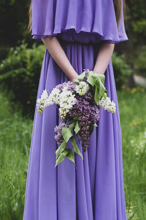 Lilac bouquet. A girl in a lilac dress holds a bouquet of lilacs of different shades in her handsの写真素材