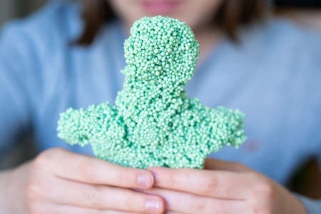 Children's hands play with a foam putty of green colorの写真素材