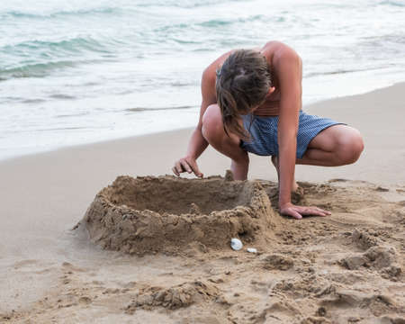 Boy on the beach plays with sand. Relax travel concept. Mediterranean sea, Spainの写真素材