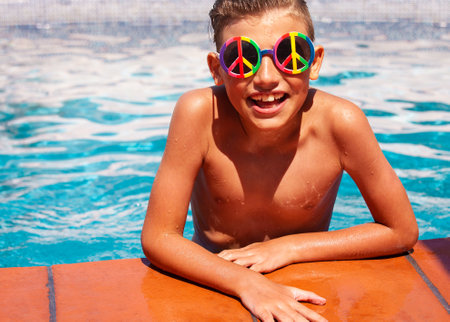 Portrait of a smiling boy in sunglasses in the swimming pool. Summer vacation