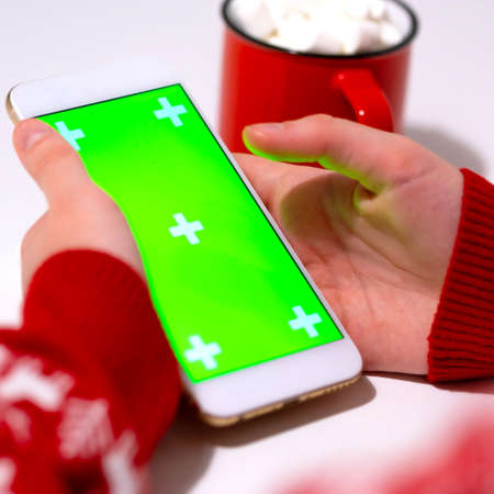 Close-up image of hands using smartphone. Mockup image blank green screen cell phone. Christmas or New Year shopping conceptの写真素材