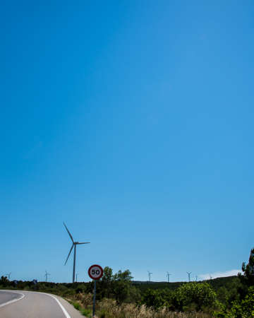 Wind turbines generating electricity over blue sky background. Green renewable alternative energy concept - wind generator turbines generating electricityの写真素材
