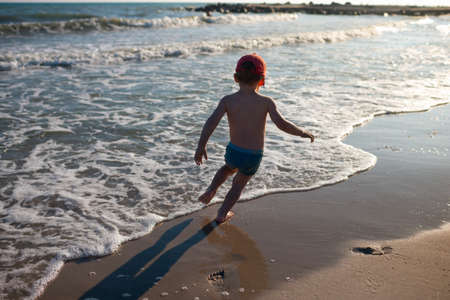 Little boy on the sand beach. Blue sea and sky. Travel, holiday and adventure concept. Summer vacation.の写真素材