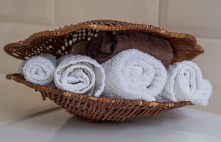 Wicker basket with white and brown towels on a white background.の写真素材
