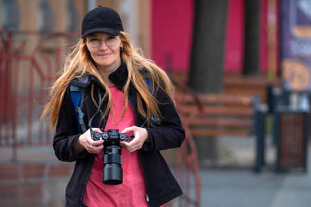 Young beautiful caucasian traveler woman with digital compact camera smiling and looking at the camera. Travel lifestyle, world travel explorer or spring tourism conceptの写真素材