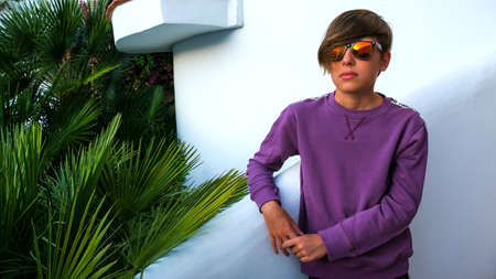 A teenager in sportswear stands on the steps by the pool. Sports purple sweatshirt on the boy....