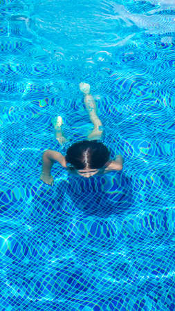 Boy in the outdoor swimming pool. Teenagers in the swimming pool. Summer vacation at the hotel or...