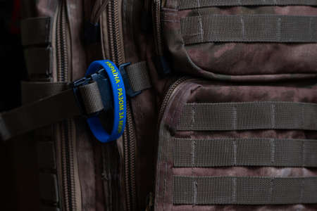 Yellow-blue bracelet with an inscription in Ukrainian: "Ukraine - together for peace!" Prevention of hostilities in Ukraine. peace concept. Military backpack of khaki color. Camouflage backpack. Military equipment is special, close upの写真素材