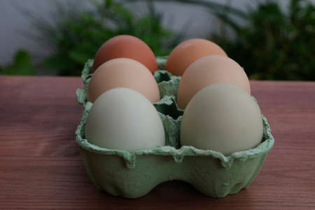Organic raw chicken eggs in a paper box on the wooden background. soft focus
