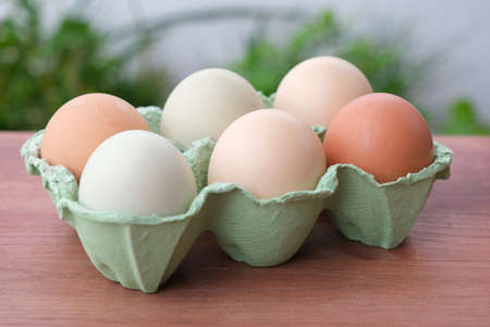 Organic raw chicken eggs in a paper box on the wooden background. soft focus