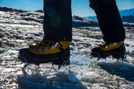 A mountaineering boot equipped with a traditional 10-point glacier trekking crampon. Mountaineer ascending up on the summit.International Mountaineering Day - 8 Augustの写真素材