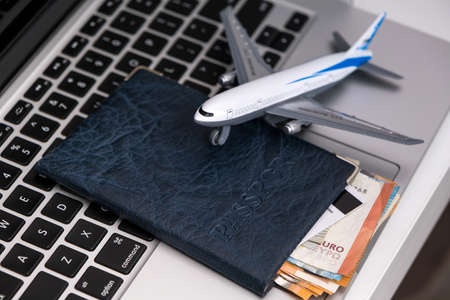 Top view of laptop computer, passport with euro banknotes and credit card, airplane.Travel and vacation, planning trip in the office or home, holiday tourism, agency tourの写真素材