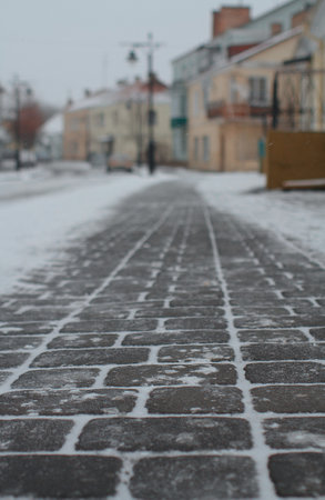 Old pavement in town Lutsk. Shallow depth of field, selective focus. Winter view of Cathedral Street in the Old Town of Lutsk. Fresh snow is falling, Christmas timeの写真素材