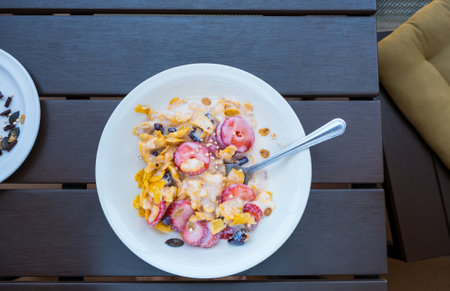 Yogurt bowl with fresh sliced strawberries and dry corn flakes. Breakfast cereal toppings served with spoon on the wooden table. Traditional corn flakes breakfast concept. healthy eating conceptの写真素材