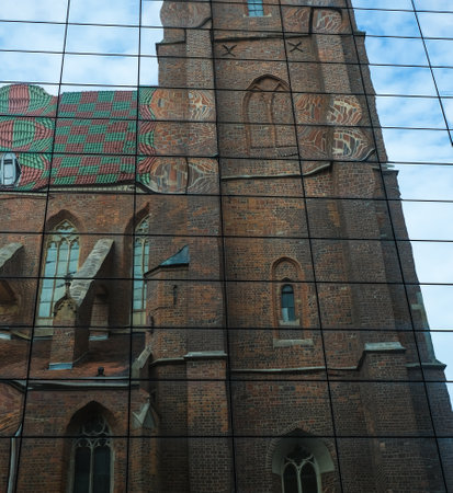 reflection of the old temple in the facade of a new modern mirror building. Old and modern architecture of Wroclaw, Polandの写真素材