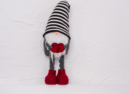 Christmas gnome in a striped hat with a heart in his hands. Decoration for Your Christmas. Christmas and New Year concept, greeting card, copy spaceの写真素材