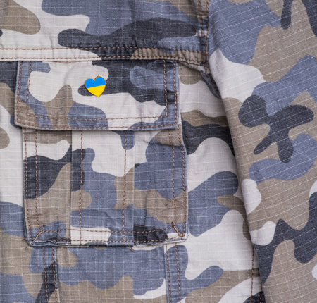 Metal badge with the flag of Ukraine in the shape of a heart on military jacket. Support for Ukraine. War in Ukraine. Ukraine flag themeの写真素材