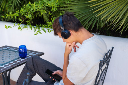 Teenage boy with mobile phone and headphones, outdoors. Youth millennial generation lifestyle and technology conceptの写真素材