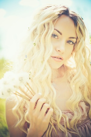 Outdoor fashion portrait of romantic blonde with dandelionsの写真素材