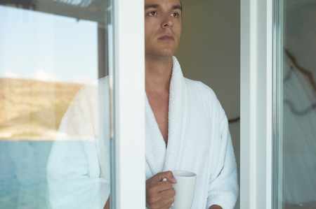 Morning portrait of handsome young man with cup of coffeeの写真素材