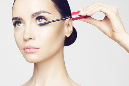 Studio fashion photo of beautiful young lady applied mascara.の写真素材
