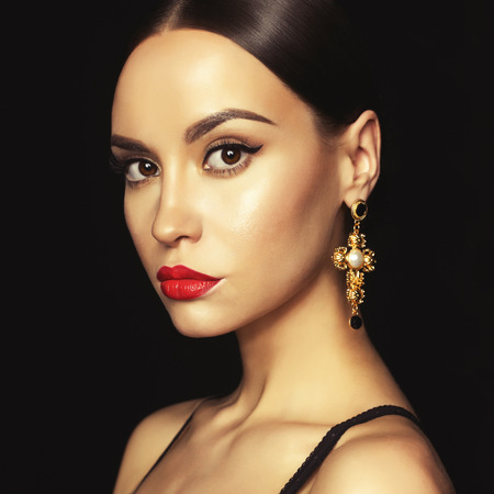 Fashion portrait of young beautiful lady with earring on black backgroundの写真素材
