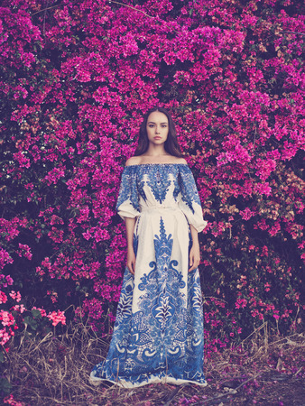 Outdoor fashion photo of beautiful young woman surrounded by flowersの写真素材