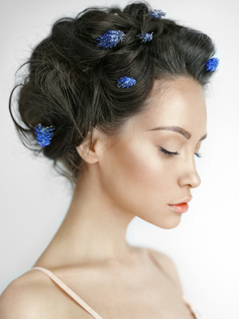 Atmospheric art-fashion portrait of beautiful young woman with blue muscari in her hair. Spring vibes. Summer freshnessの写真素材