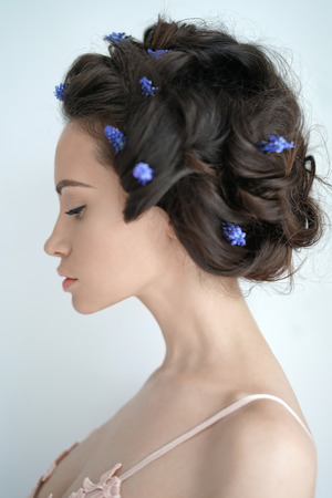 Atmospheric art-fashion portrait of beautiful young woman with blue muscari in her hair. Spring vibes. Summer freshnessの写真素材